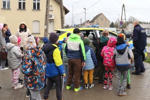 Policjant gości przedszkolaków w posterunku policji, pokazuje radiowóz i edukuje dzieci