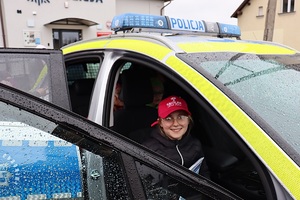Policjant gości przedszkolaków w posterunku policji, pokazuje radiowóz i edukuje dzieci