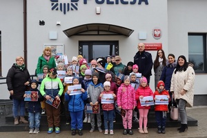 Policjant gości przedszkolaków w posterunku policji, pokazuje radiowóz i edukuje dzieci