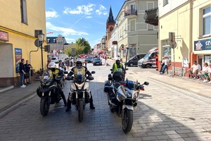 Policyjny motocyklista zabezpiecza prawidłowy przebieg wyścigu kolarskiego