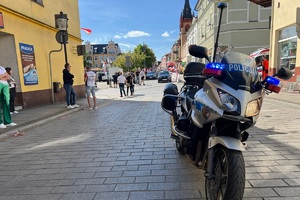 Policyjny motocyklista zabezpiecza prawidłowy przebieg wyścigu kolarskiego
