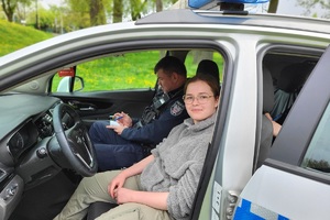 Policjanci podczas pikniku charytatywnego prowadzą pokaz posłuszeństwa psa i prezentują sprzęt służbowy