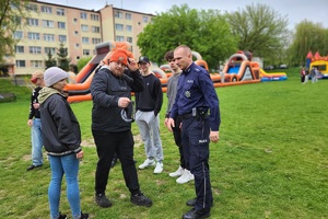 Policjanci podczas pikniku charytatywnego prowadzą pokaz posłuszeństwa psa i prezentują sprzęt służbowy