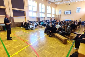 Policjant wydziału prewencji prowadzi zajęcia z uczniami szkoły ponadpodstawowej