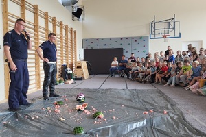Policjanci prowadzący zajęcia z uczniami na temat bezpieczeństwa na drodze