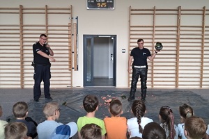 Mundurowi prowadzą pogadankę na temat poruszania się hulajnogami po drodze i używania kasków