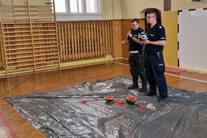 Mundurowi prowadzą pogadankę na temat poruszania się hulajnogami po drodze i używania kasków