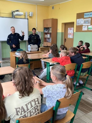 Policjanci podczas pogadanki prezentują walizkę edukacyjną