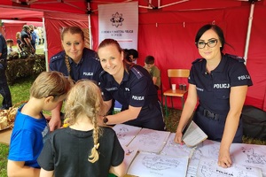 Policjanci i pracownicy OPS podczas pikniku rodzinnego zabawiają mieszańców miasta