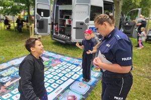 Policjanci i pracownicy OPS podczas pikniku rodzinnego zabawiają mieszańców miasta