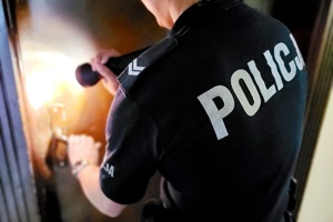 Policjantka świeci latarkę na drzwi