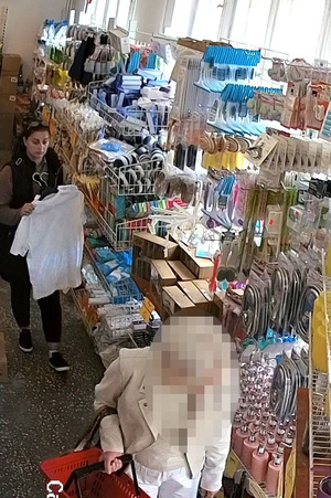 Kobieta trzymająca ubrania na wieszakach, która okradła inną klientkę