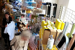 Kobieta trzymająca ubrania na wieszakach, która okradła inną klientkę