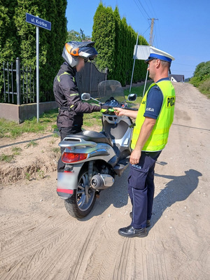 Policjant wręcza motocykliście szelki odblaskowe.