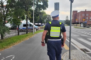 Policjant kontroluje oznakowanie przy placówkach oświatowych