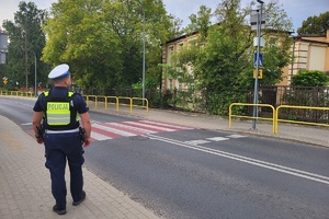 Policjant kontroluje oznakowanie przy placówkach oświatowych
