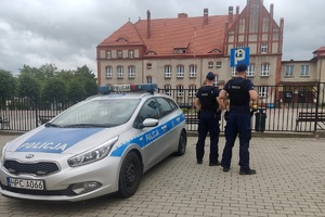 Policjant kontroluje oznakowanie przy placówkach oświatowych