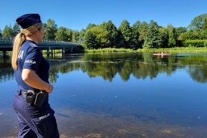 Policjantka obserwuje brzeg rzeki i pływających kajakarzy