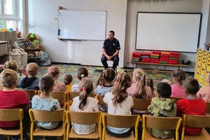 Policjant siedzi na krześle przed grupą dzieci