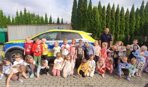 Grupowe zdjęcie przedszkolaków z policjantem przy radiowozie