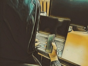 Mężczyzna siedzi przy biurku, trzyma telefon w ręku