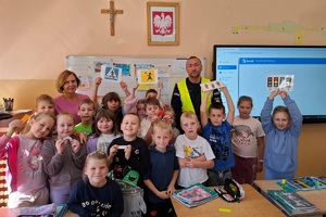 Dzielnicowy prowadzi z uczniami lekcję bezpieczeństwa a następnie ćwiczenia praktyczne na drodze