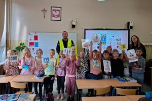 Dzielnicowy prowadzi z uczniami lekcję bezpieczeństwa a następnie ćwiczenia praktyczne na drodze