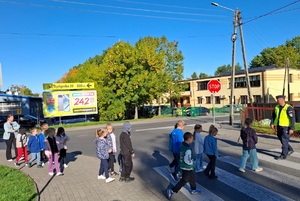 Dzielnicowy prowadzi z uczniami lekcję bezpieczeństwa a następnie ćwiczenia praktyczne na drodze