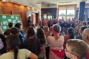 Policjantka na korytarzu szkolnym rozmawia z uczniami i prowadzi pogadankę