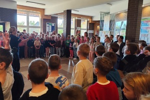 Policjantka na korytarzu szkolnym rozmawia z uczniami i prowadzi pogadankę