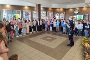 Policjantka na korytarzu szkolnym rozmawia z uczniami i prowadzi pogadankę