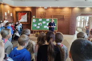 Policjantka na korytarzu szkolnym rozmawia z uczniami i prowadzi pogadankę