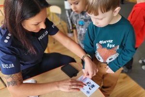 Policjantka wykonuje dzieciom pamiątkowe kartki z odbitkami ich linii papilarnych
