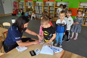 Policjantka wykonuje dzieciom pamiątkowe kartki z odbitkami ich linii papilarnych