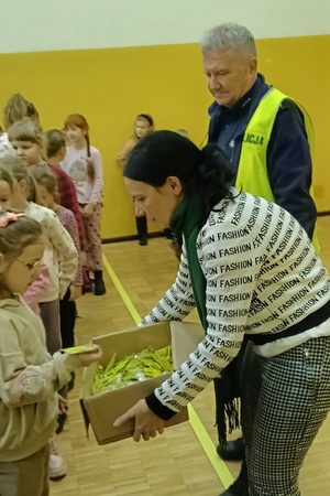 Policjant prowadzi pogadankę i praktyczną lekcję przechodzenia przez jezdnię