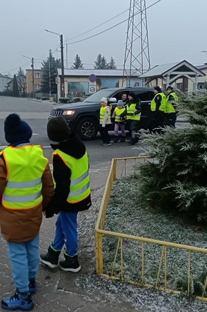 Policjant prowadzi pogadankę i praktyczną lekcję przechodzenia przez jezdnię