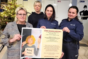 Pracownik PCPR, Pani psycholog i policjantki trzymające plakat dotyczący przeciwdziałania przemocy