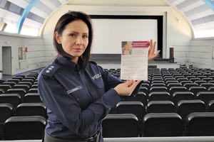 Policjantka trzymająca ulotkę dot. przeciwdziałania przemocy