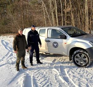 Policjant i Funkcjonariusz ze Straży Łowieckiej przy pojeździe.