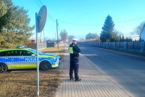 Policjant stoi obok radiowozu