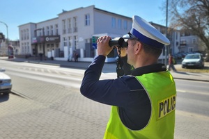 Policjant ruchu drogowego obserwuje kierowców za pomocą lornetki
