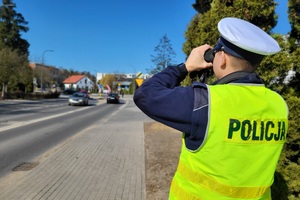 Policjant ruchu drogowego obserwuje kierowców za pomocą lornetki