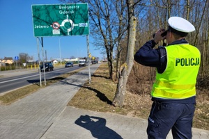 Policjant ruchu drogowego obserwuje kierowców za pomocą lornetki
