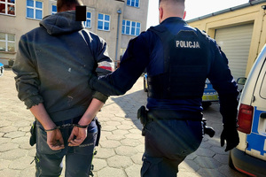 Policjant prowadzi zatrzymanego mężczyznę