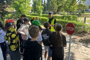 Policjant ruchu drogowego rozmawia z dziećmi i egzaminuje ich na kartę rowerową