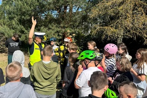 Policjant ruchu drogowego rozmawia z dziećmi i egzaminuje ich na kartę rowerową