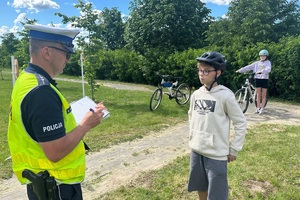 Policjant ruchu drogowego rozmawia z dziećmi i egzaminuje ich na kartę rowerową
