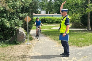 Policjant ruchu drogowego rozmawia z dziećmi i egzaminuje ich na kartę rowerową