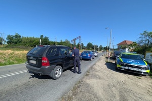 Policjant wręcza ulotki kierowcom na przejeździe kolejowym
