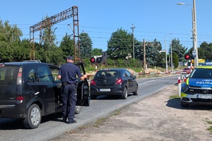 Policjant wręcza ulotki kierowcom na przejeździe kolejowym